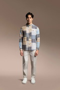 A man stands against a warm beige studio background wearing a long-sleeve button-up shirt Onésimus Men's Casual Shirts: Geometric Prints with light gray trousers and white sneakers.