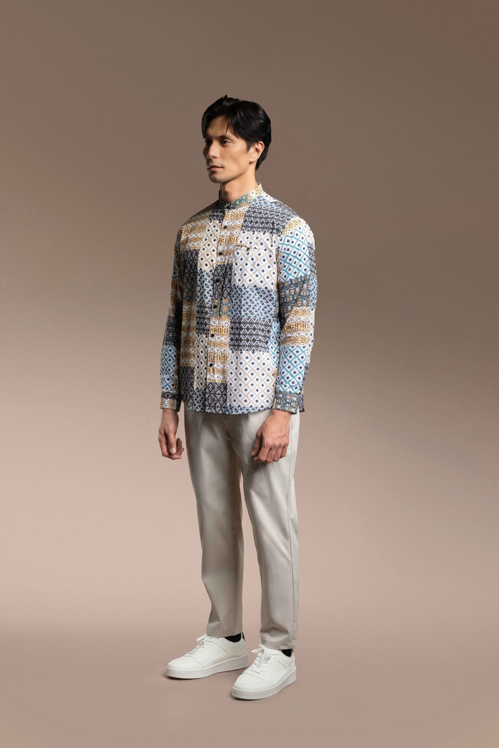 Man wearing a Onésimus Men's Casual Shirts: Geometric Prints and light pants on a beige background