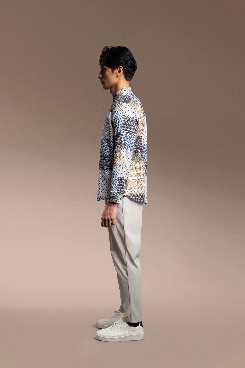 Man wearing a patterned Onésimus Men's Casual Shirts: Geometric Prints and light-colored pants against a beige background