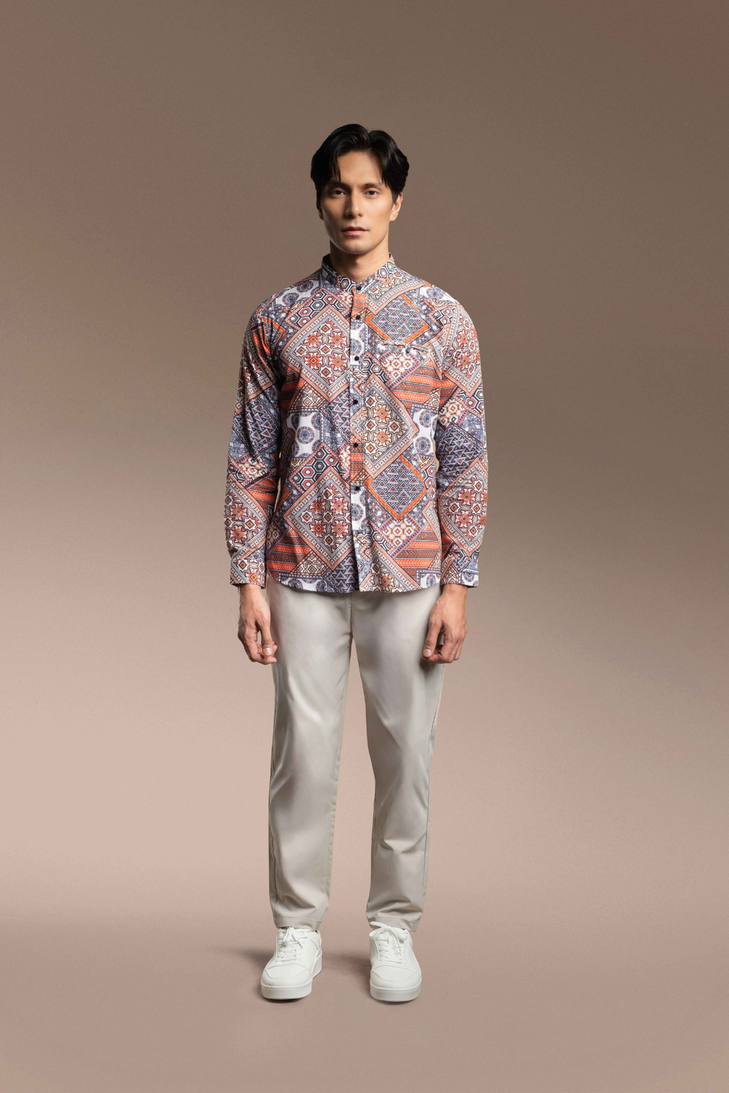 A man stands against a beige studio background wearing a Onésimus Men's Casual Shirts in Pure Cotton paired with light beige trousers and white sneakers.